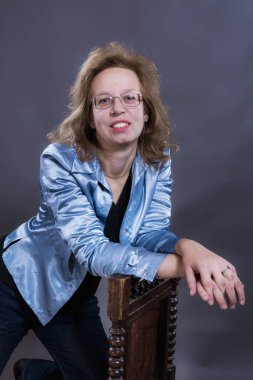 Mavi kot pantolon ve mavi ceket giymiş 40 yaşında neşeli bir kadın.