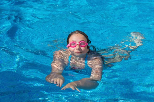 Dívka v brýlích plavat v modrém bazénu. — Stock fotografie