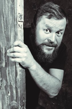 Neşeli sakallı adam kapıdan dışarı bakıyor.