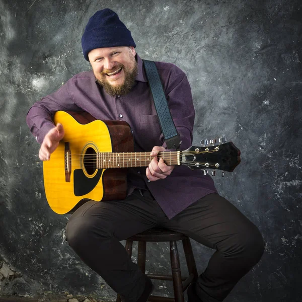 Mature musician plays acoustic guitar emotional studio portrait. — Stock Photo, Image