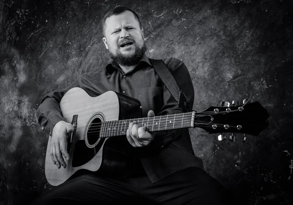 Mature musician plays acoustic guitar emotional studio portrait. — Stock Photo, Image