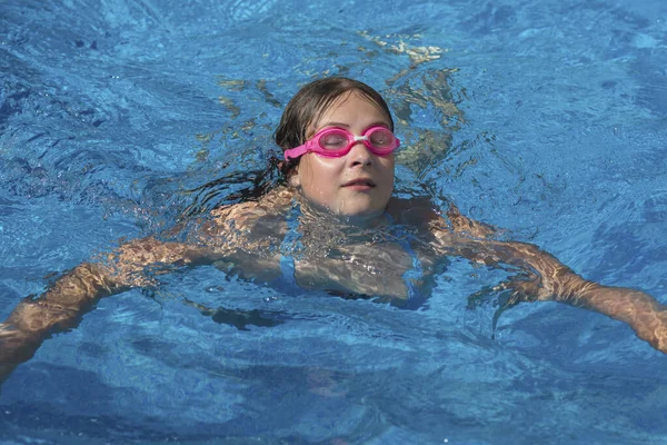 Mädchen mit Brille schwimmt im blauen Schwimmbad. — Stockfoto