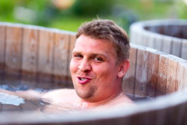 Adam dışarıda tahta bir kasede banyo yapıyor.