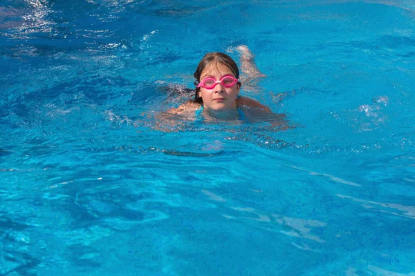 Szemüveges lány úszik a kék uszodában. — Stock Fotó