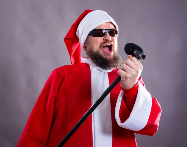 Bearded rocke med micriphome klädd i Santa Claus kostym — Stockfoto