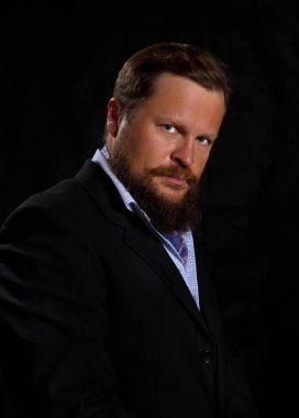 Düşünceli, sakallı, takım elbiseli adam.