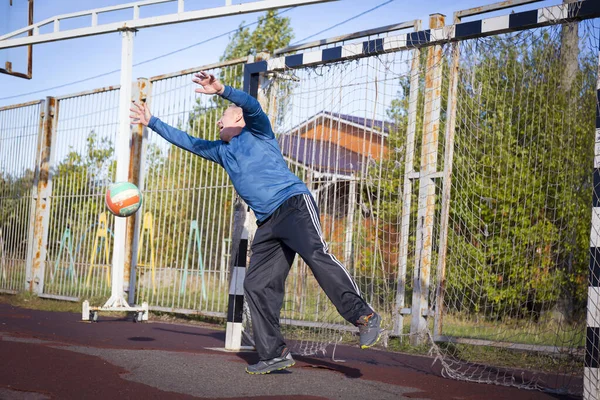 Homem idoso ativo jogando futebol em campo de esportes. — Fotografia de Stock