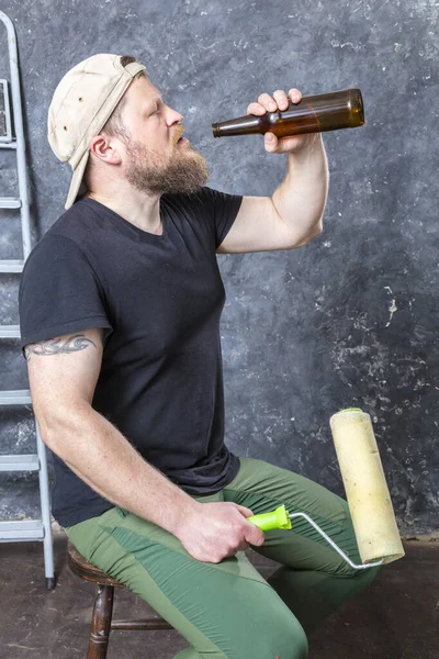 Vreugdevolle bebaarde voorman heeft een pauze met een fles bier — Stockfoto