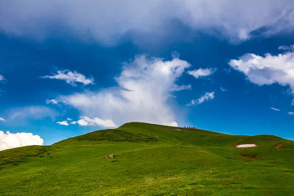 Красивый горный пейзаж в горах Кавказа с облаками, голубым небом и линией всадников далеко — стоковое фото