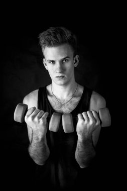 Genç sporcu, siyah arka planda aptal stüdyo portresiyle egzersiz yapıyor..