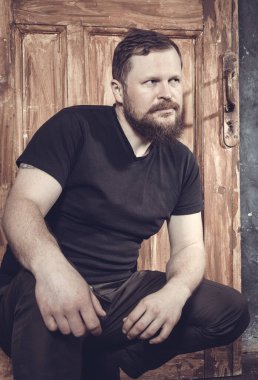 Olgun sakallı adam klasik kapının arkasında oturuyor.