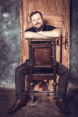 Olgun sakallı adam klasik kapının arkasında oturuyor.