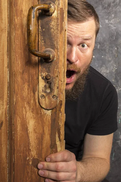 Fröhlicher bärtiger Mann blickt aus der Tür — Stockfoto