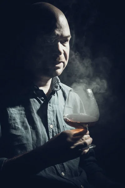 Vaste kale man in shirt met glas whisky en rook — Stockfoto