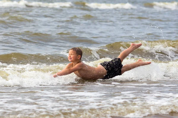 若いです陽気な少年持っています楽しいです海の波. — ストック写真