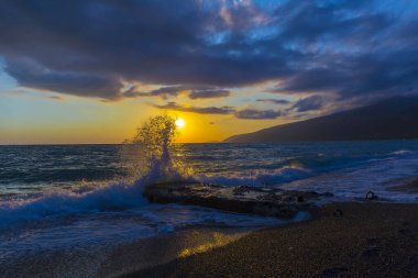 Gün batımında dalgalarla güzel bir kıyı sahnesi