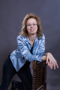 Mavi kot pantolon ve mavi ceket giymiş 40 yaşında neşeli bir kadın.