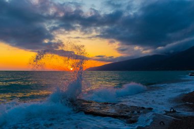 Gün batımında dalgalarla güzel bir kıyı sahnesi