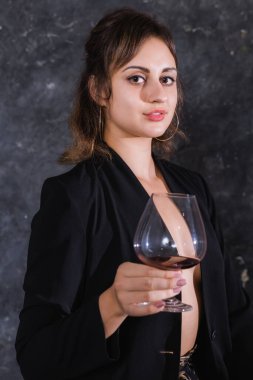 Siyah ceketli güzel bir bayan ve bir kadeh şarap.