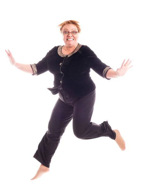 Middle aged woman in black jacket and trousers jumping Royalty Free Stock Images