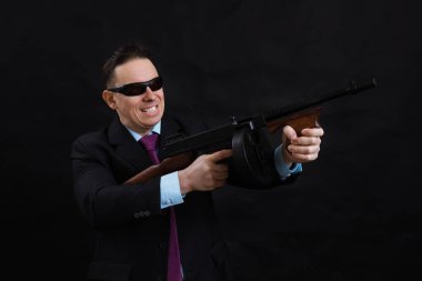 Güneş gözlüklü, takım elbiseli, Tommy Gun 'lı olgun gangster.