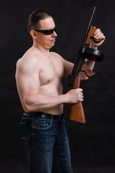 Dojrzały mężczyzna w okularach przeciwsłonecznych i nagim tułowiu z pistoletem Tommy 'ego — Zdjęcie stockowe