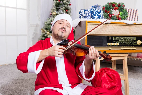 Barbudo vestido con traje de Santa Claus tocando violín —  Fotos de Stock