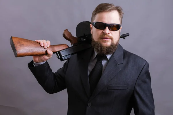Volwassen man in zonnebril gekleed in pak met tommy gun — Stockfoto