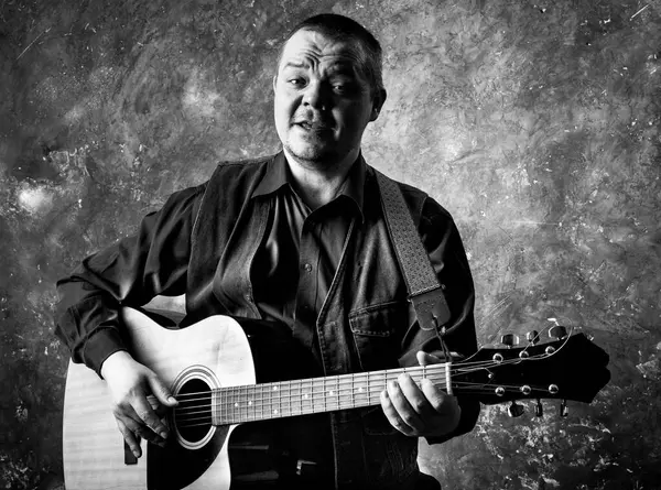 Mature musician plays acoustic guitar emotional studio portrait. Stock Image