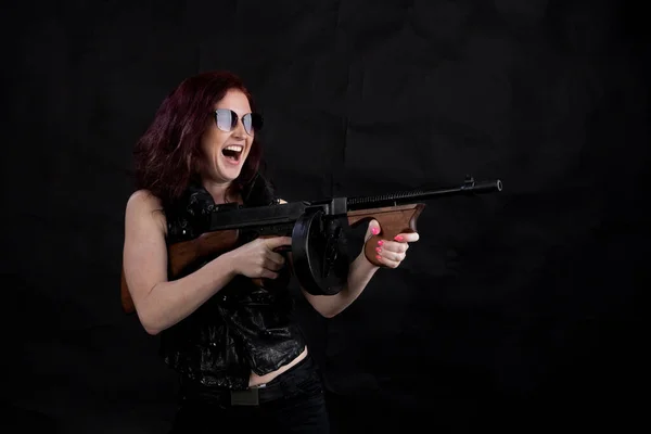 Beautiful woman dressed in black jacket with a gun — Stock Photo, Image