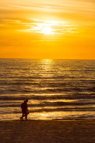 Menschen am Sandstrand bei Sonnenuntergang — Stockfoto