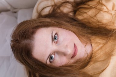 Çekici yaşlı kadın kanepeye uzanıp kameraya bakıyor.