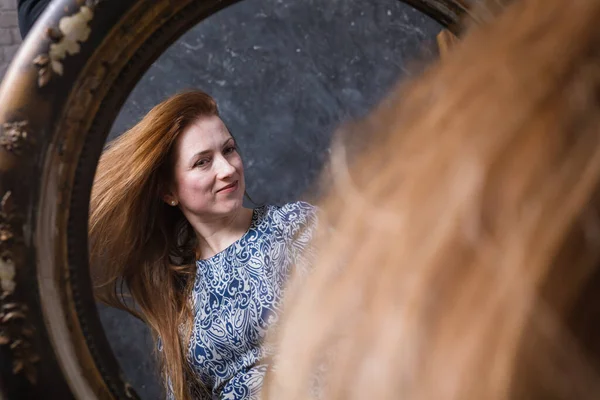 Vrolijke middelbare leeftijd vrouw kijkt in vintage stijl spiegel — Stockfoto