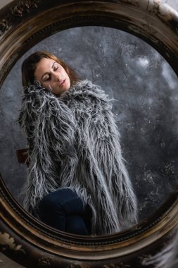 Güzel genç bir kadın aynaya bakıyor.