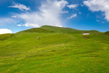 Kafkasya dağlarındaki güzel dağ manzarası Bulutlar, mavi gökyüzü ve uzaklardaki at binicilerinin çizgisi