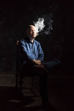 Olgun kel adam sigara içiyor, siyah arka planda portre çiziyor..