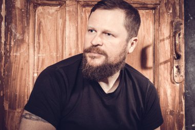 Olgun sakallı adam klasik kapının arkasında oturuyor.