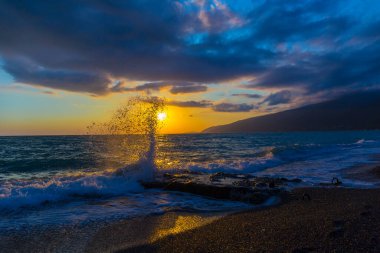 Gün batımında dalgalarla güzel bir kıyı sahnesi