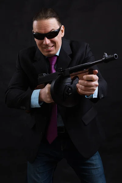 Maduro gangster em óculos de sol vestido de terno com arma de tommy — Fotografia de Stock
