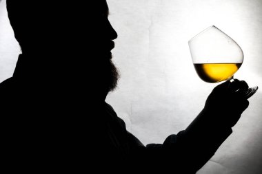 Erkek silueti beyaz arka planda viski tadıyor.