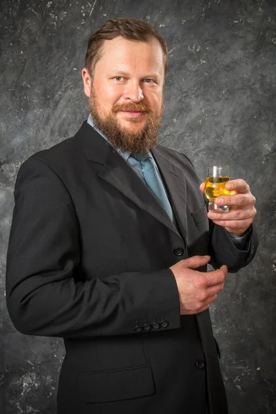 Fast skäggig man i kostym provsmakning whisky i ett glas — Stockfoto