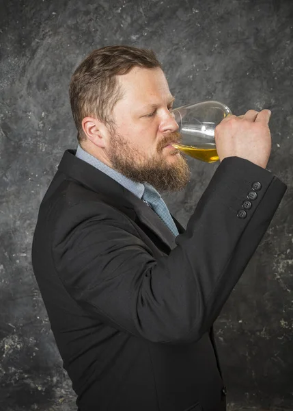 Vaste bebaarde man in pak proeft whisky in een glas — Stockfoto