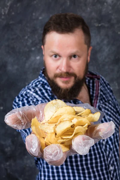 Homem barbudo sólido em roupas casuais com monte de batatas fritas — Fotografia de Stock