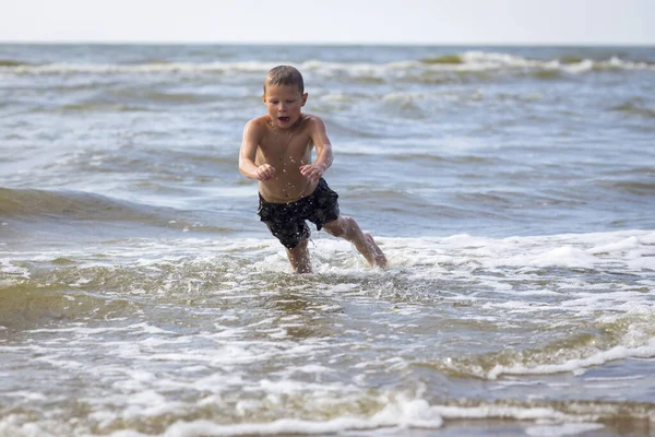 若いです陽気な少年持っています楽しいです海の波. — ストック写真