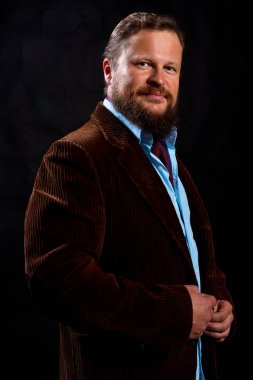 Siyah arka planda takım elbise giymiş şık sakallı bir adam..