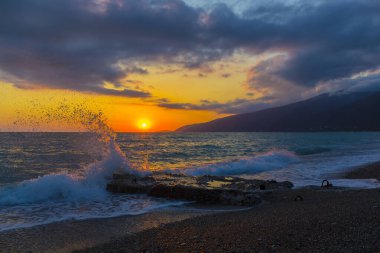 Gün batımında dalgalarla güzel bir kıyı sahnesi