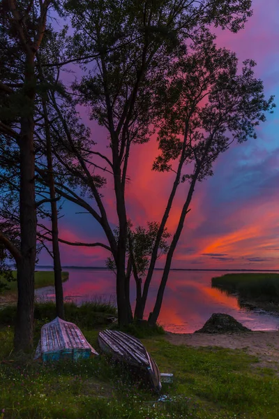 Красочный закат над озерным летним пейзажем с лодками на берегу. — стоковое фото