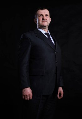 Orta yaşlı, takım elbiseli, sağlam bir adam.