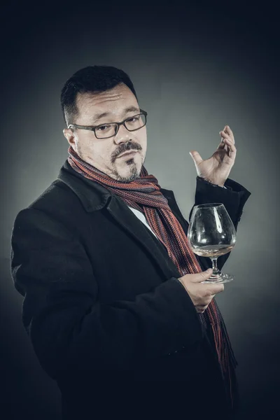 Homem alegre sólido em casaco e lenço de pé com copo de vinho — Fotografia de Stock