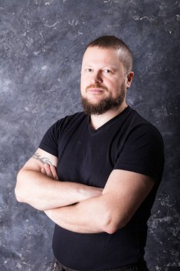 Tişört stüdyo resmi giymiş sakallı bir adam.